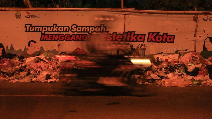 Pengendara melintas di dekat tumpukan sampah di Banguntapan, Bantul, DI Yogyakarta, Selasa (14/5/2024). Penumpukan sampah terjadi di sejumlah lokasi di Kota Yogyakarta, Bantul dan Sleman disebabkan belum optimalnya fasilitas pengolahan sampah tiap kota/kabupaten dampak penutupan permanen TPST Piyungan. ANTARA FOTO/Hendra Nurdiyansyah/rwa.