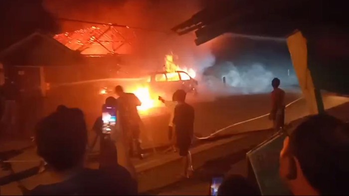 Petugas berusaha memadamkan api yang membakar mobil dan rumah warga di tepi jalan nasional, Kecamatan Tambak, Kabupaten Banyumas, Selasa (14/5/2024) malam.