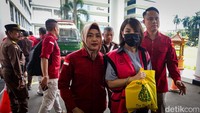 Tangan Helena Lim diborgol saat memenuhi panggilan. Ia juga menenteng tas belanja minimarket di tangannya.   
