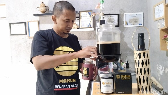 Amar Thohir pemilik usaha madu asli Kuningan Makun sedang mengisi ulang gelas toples dengan madu mellifera untuk konsumennya