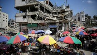 Pedagang Palestina menjual barang di dekat gedung Bank of Jordan yang hancur pada awal Mei lalu.  
