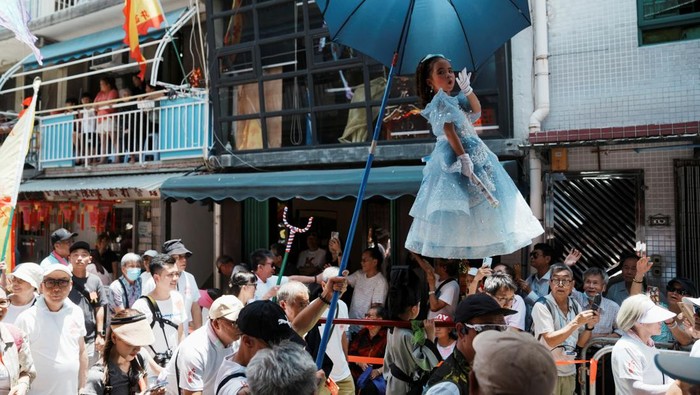 A child stands above the crowd with the support of an elaborate rig of hidden metal rods during the Bun Festival parade at Cheung Chau Island in Hong Kong, China May 15, 2024. REUTERS/Lam Yik