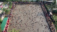 Foto udara sejumlah warga menangkap ikan saat tradisi Ngubek Empang di Cilodong, Depok, Jawa Barat, Kamis (16/5/2024).   