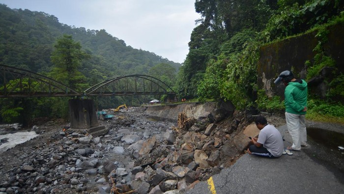Warga menyaksikan alat berat bekerja untuk menangani jalan putus di kawasan Lembah Anai, Nagari Singgalang, Tanah Datar, Sumatera Barat, Kamis (16/5/2024).  Pemerintah mengerjakan sebanyak 16 titik jalan rusak di sepanjang jalan nasional Padang - Bukittinggi termasuk jalan putus akibat banjir bandang tersebut dan akan melakukan penanganan darurat sebelukan pembangunan permanen. ANTARA FOTO/Iggoy el Fitra/Spt.