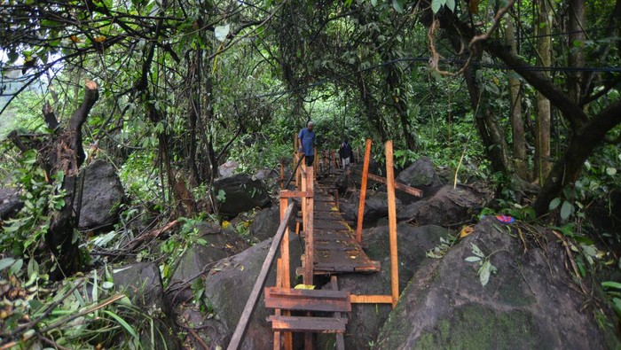 Warga melintasi kawasan cagar alam Lembah Anai, di Nagari Singgalang, Tanah Datar, Sumatera Barat, Kamis (16/5/2024). Pasca terputusnya jalan nasional Lembah Anai akibat banjir bandang, warga dan pekerja membuat jalan darurat di kawasan hutan itu bagi warga sekitar dan anak sekolah dengan menggunakan kayu dan papan. ANTARA FOTO/Iggoy el Fitra/tom.