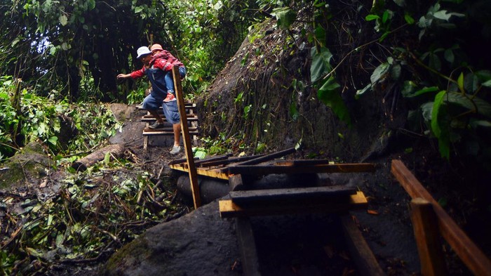 Warga melintasi kawasan cagar alam Lembah Anai, di Nagari Singgalang, Tanah Datar, Sumatera Barat, Kamis (16/5/2024). Pasca terputusnya jalan nasional Lembah Anai akibat banjir bandang, warga dan pekerja membuat jalan darurat di kawasan hutan itu bagi warga sekitar dan anak sekolah dengan menggunakan kayu dan papan. ANTARA FOTO/Iggoy el Fitra/tom.