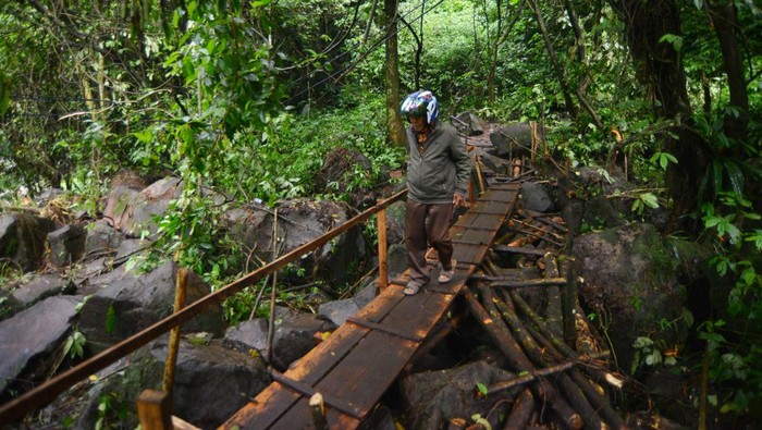Warga melintasi kawasan cagar alam Lembah Anai, di Nagari Singgalang, Tanah Datar, Sumatera Barat, Kamis (16/5/2024). Pasca terputusnya jalan nasional Lembah Anai akibat banjir bandang, warga dan pekerja membuat jalan darurat di kawasan hutan itu bagi warga sekitar dan anak sekolah dengan menggunakan kayu dan papan. ANTARA FOTO/Iggoy el Fitra/tom.