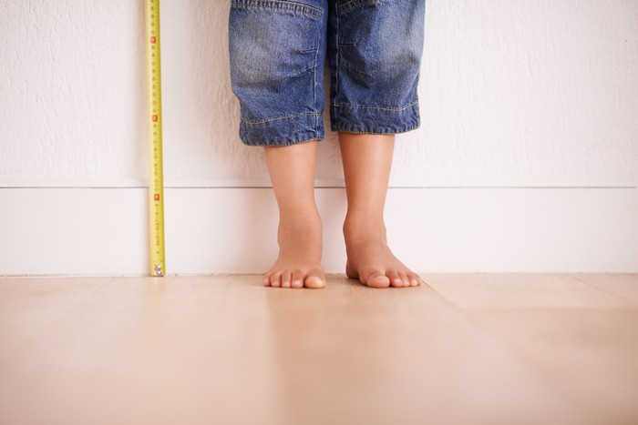 Cropped shot of a young boy standing next to a tape measure