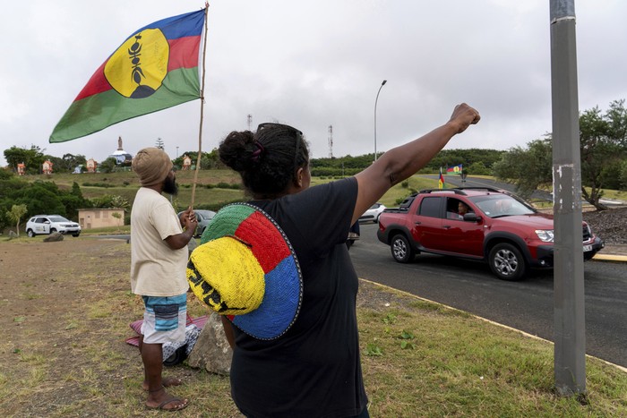 A woman waves a Kanak and Socialist National Liberation Front (FLNKS) flag in Noumea, New Caledonia, Wednesday May 15, 2024. France has imposed a state of emergency in the French Pacific territory of New Caledonia. The measures imposed on Wednesday for at least 12 days boost security forces powers to quell deadly unrest that has left four people dead, erupting after protests over voting reforms. (AP Photo/Nicolas Job)