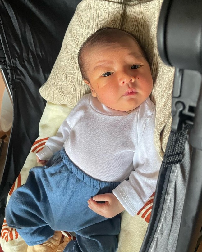 Wanita 27 tahun itu tampak memamerkan foto putranya ketika masih bayi. Mengenakan setelan berwarna putih dan biru, baby Naka tampak menggemaskan dengan pipi tembamnya. Foto: Instagram: @indahpermatas