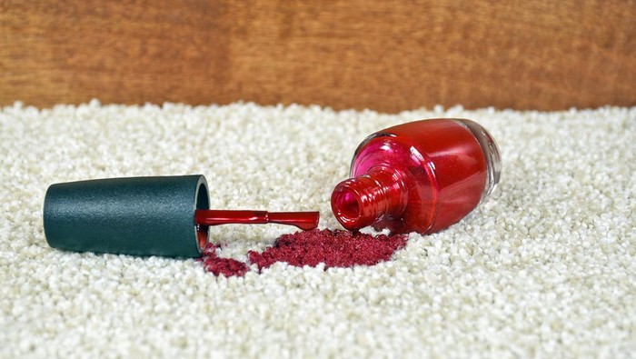 Close up of bright red nail polish on light colored carpet