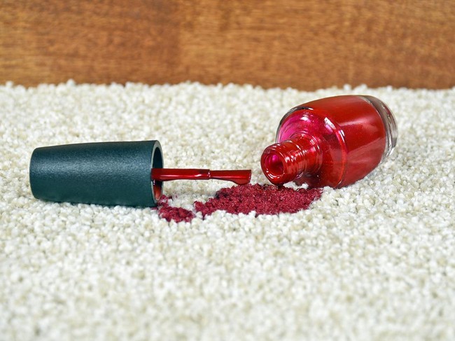 Close up of bright red nail polish on light colored carpet