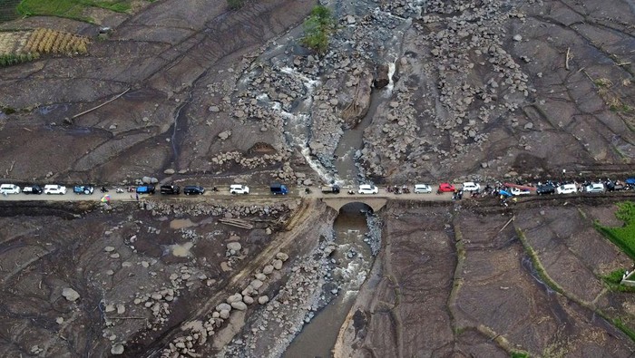 Antrean kendaraan di jalan terdampak banjir bandang Foto udara kendaraan antre melewati jembatan yang terdampak banjir bandang di jalan penghubung Nagari Rambatan dengan Nagari Limo Kaum, Tanah Datar, Sumatera Barat, Jumat (17/5/2024). Jalan pedesaan yang menjadi jalur alternatif ke kabupaten lain pascabanjir bandang lahar dingin Gunung Marapi itu dipadati kendaraan yang harus melintas secara bergantian karena ukuran jembatan yang kecil. ANTARA FOTO/Iggoy el Fitra/tom.