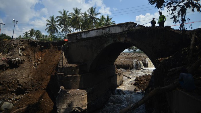 Petugas kepolisian melihat kondisi jembatan yang rusak di Jorong Panti, Nagari Rambatan, Tanah Datar, Sumatera Barat, Minggu (19/5/2024). Jembatan yang diterjang banjir bandang sepekan lalu itu kini terputus dan akses dari Kabupaten Solok terpaksa dialihkan. ANTARA FOTO/Iggoy el Fitra/YU