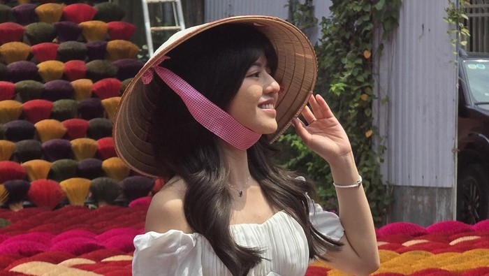 Vonzy Onic tampil cantik dengan gaun putih dan topi caping di Incense Village Vietnam. Pesonanya ditangkap lewat kamera Samsung Galaxy S24.