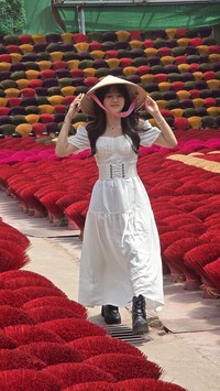 Vonzy Onic tampil cantik dengan gaun putih dan topi caping di Incense Village Vietnam. Pesonanya ditangkap lewat kamera Samsung Galaxy S24.