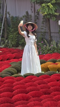 Vonzy Onic tampil cantik dengan gaun putih dan topi caping di Incense Village Vietnam. Pesonanya ditangkap lewat kamera Samsung Galaxy S24.