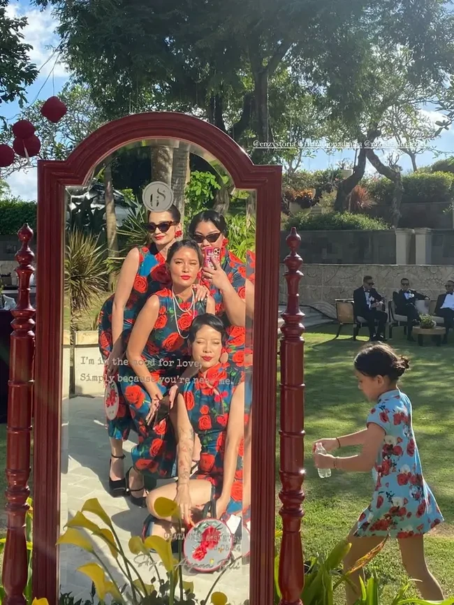 Tampil kompak bersama para bridesmaid lainnya. Enzy terlihat mengenakan seragam dress cheongsam tanpa lengan bermotif floral. Penampilannya semakin terlihat stylish dengann kaca mata hitam. Foto: Instagram/@enzystoria
