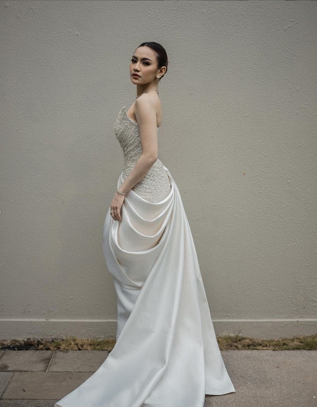 Garis leher asimetris membuat gaun terlihat unik. Lipitan dengan ekor menjuntai menambah kesan anggun dan feminin. Foto: Instagram/@axioo @hiantjen @dhirmanputra