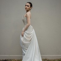 Garis leher asimetris membuat gaun terlihat unik. Lipitan dengan ekor menjuntai menambah kesan anggun dan feminin. Foto: Instagram/@axioo @hiantjen @dhirmanputra