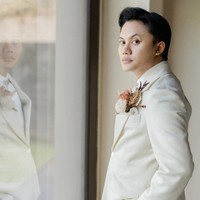 Pengantin pria, Rizky Febian, memilih setelan tuksedo dari koleksi Henri Winata. Tampilannya chic sekaligus elegan dengan padanan warna putih dan ivory. Foto: Instagram/@axioo @hiantjen @dhirmanputra