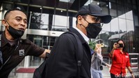 Rahmady keluar gedung dengan mengenakan kemeja putih dan jaket hitam. Dia juga memakai topi dan masker hitam.