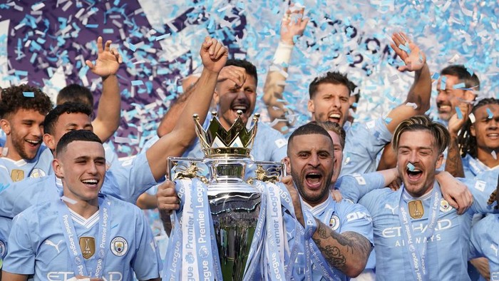 Manchester Citys Kyle Walker, center, celebrates with the Premier League trophy with Manchester Citys Phil Foden, and Manchester Citys Jack Grealish after the English Premier League soccer match between Manchester City and West Ham United at the Etihad Stadium in Manchester, England, Sunday, May 19, 2024. Manchester City clinched the English Premier League on Sunday after beating West Ham in their last match of the season. (AP Photo/Dave Thompson)
