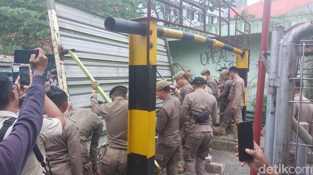 Satpol PP Kota Bogor membuka akses jalan warga menuju Pasar Jambu Dua yang sempat ditutup pihak pengelola mal. (M Sholihin/detikcom)