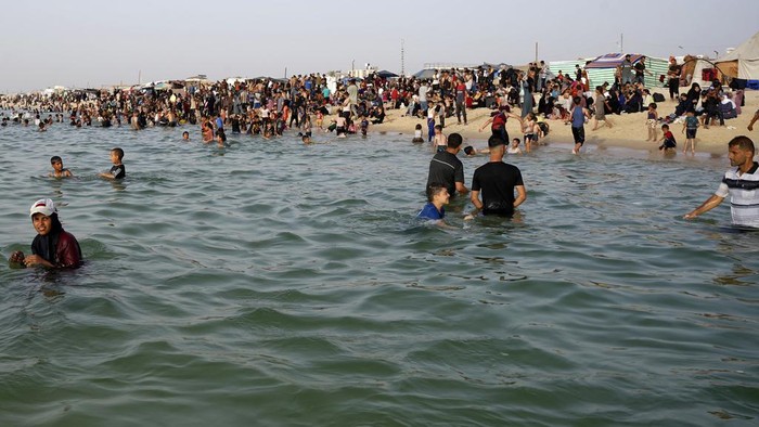 Palestinian family members displaced by the ongoing war with Israel, enjoy the day along the Mediterranean Sea during a heat wave at Khan Younis beach, southern Gaza Strip, Monday, May 20, 2024. (AP Photo/Saher Alghorra)