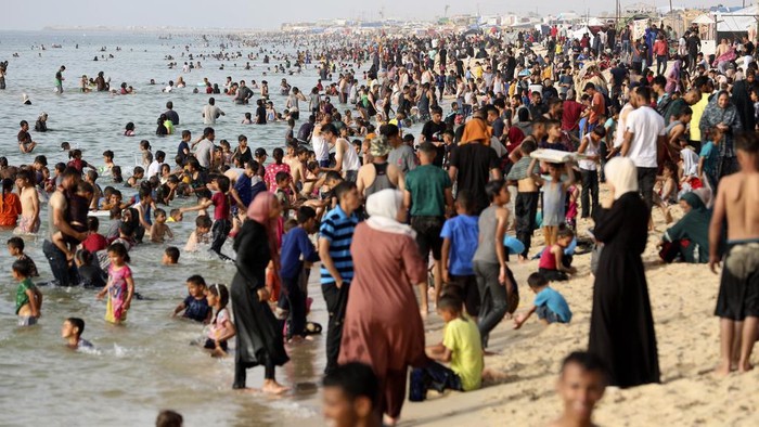 Palestinian family members displaced by the ongoing war with Israel, enjoy the day along the Mediterranean Sea during a heat wave at Khan Younis beach, southern Gaza Strip, Monday, May 20, 2024. (AP Photo/Saher Alghorra)