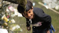 Seorang anak laki-laki membasahi wajahnya agar terasa segar. Hal ini mereka lakukan agar tetap segar ditengah teriknya matahari.