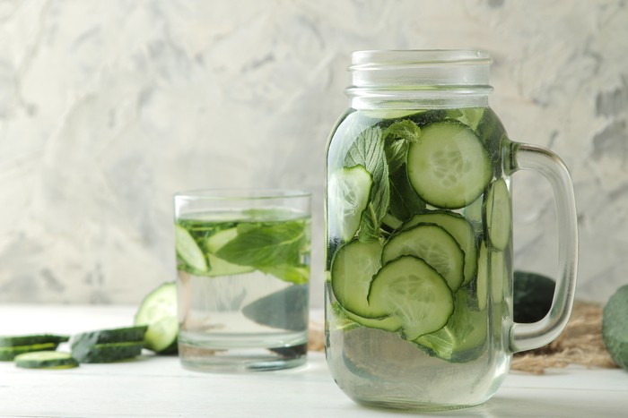 water with cucumber. Refreshing diet water with cucumber in a glass cup on a light background. detox drink concept. summer refreshing drink.
