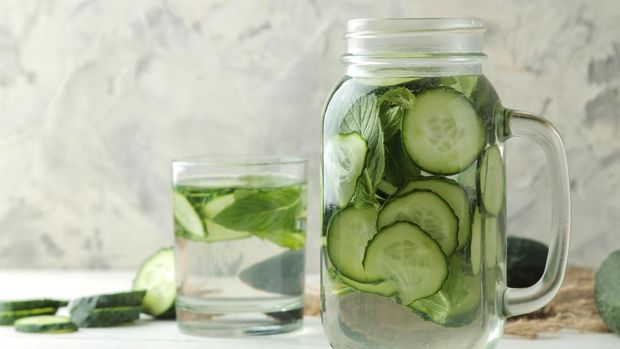 water with cucumber. Refreshing diet water with cucumber in a glass cup on a light background. detox drink concept. summer refreshing drink.