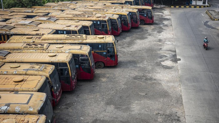 Warga melintas di dekat bus Transjakarta yang terbengkalai terparkir di kawasan Terminal Pulogebang, Jakarta Timur, Rabu (22/5/2024). Kepala Dinas Perhubungan (Dishub) Provinsi DKI Jakarta SyafrinLiputo akan melakukan penghapusan dan penjualan aset 417 bus TransJakarta karena bus-bus tersebut sudah tidak layak pakai jika dilihat dari usianya. ANTARA FOTO/Dhemas Reviyanto/YU