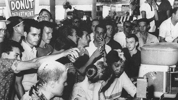 Foto ini, diambil oleh Fred Blackwell pada tanggal 28 Mei 1963, menggambarkan tiga aktivis hak-hak sipil – John Salter, Joan Trumpauer, dan Anne Moody – mengalami pelecehan di konter makan siang Woolworth. Saat mereka duduk di konter khusus kulit putih, kerumunan yang marah menghujani mereka dengan saus tomat, gula, dan mustard. Para pengunjuk rasa pemberani ini berafiliasi dengan Tougaloo College, sebuah institusi yang secara historis berkulit hitam yang memainkan peran penting dalam gerakan hak-hak sipil di Mississippi. Foto: HistoryDefined