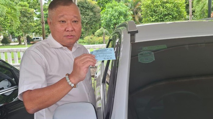 Ketua Komisi I DPRD Kota Batam, Lik Khai menunjukkan karcis parkir dan stiker berlangganan. (dok. Istimewa)