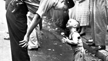 Seorang polisi dengan manis menghentikan bocah kecil dari persimpangan karena adanya sebuah parade, 1958. (Foto: Brightside)