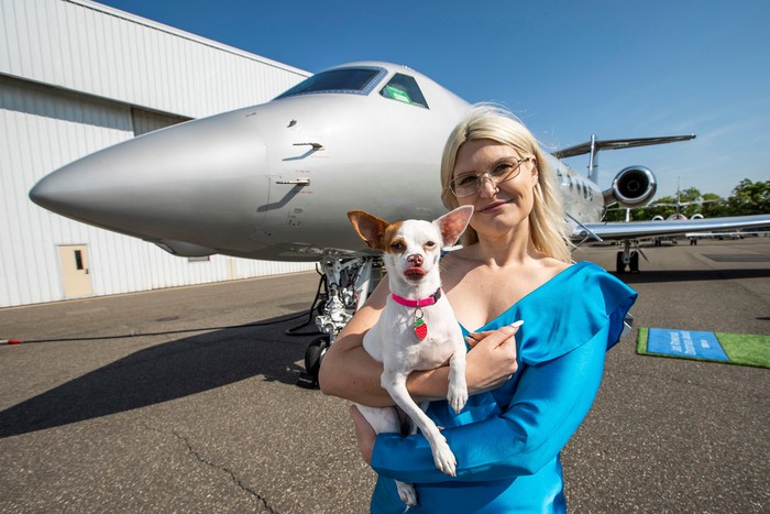 A woman shows a dog’s boarding pass after boarding a plane during a press event introducing Bark Air, an airline for dogs, at Republic Airport in East Farmingdale, New York, May 21, 2024. REUTERS/Eduardo Munoz