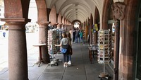 Orang-orang berdiri di bawah lengkungan Balai Kota Tua Leipzig.