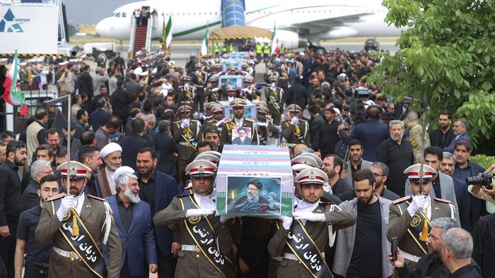 Pelayat Penuhi Jalanan Iran Saat Prosesi Pemakaman Presiden Ebrahim Raisi In this photo released by the Iranian Presidency Office, mourners gather around a truck carrying the flag-draped coffins of President Ebrahim Raisi and his companions who were killed in a helicopter crash on Sunday in a mountainous region of the country's northwest, in their funeral ceremony in the city of Tabriz, Iran, Tuesday, May 21, 2024. (Iranian Presidency Office via AP)