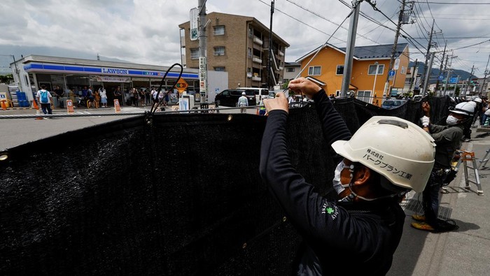 Penampakan Kain Hitam Penghalang Pemandangan Gunung Fuji yang Viral Workers erect a barrier to block the view of a popular Mount Fuji photo spot, near a convenience store in Fujikawaguchiko town, Yamanashi prefecture, Japan, May 21, 2024. REUTERS/Kim Kyung-Hoon