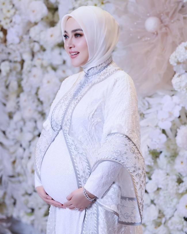 Syahrini tampak mengenakan gamis putih dengan outer lace berhias bordir aksen abu-abu. Jilbabnya ditata dengan gaya simple yang juga bernuansa putih. Foto: instagram Syahrini
