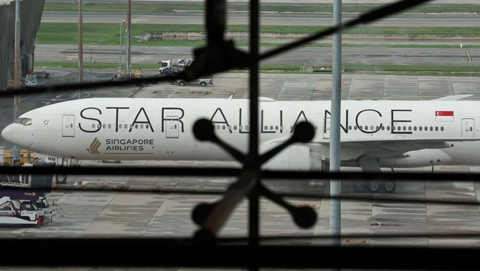 A woman eats as the Singapore Airlines aircraft for flight SQ321 is parked on the tarmac after an emergency landing at Suvarnabhumi International Airport, in Bangkok, Thailand, May 22, 2024. REUTERS/Athit Perawongmetha