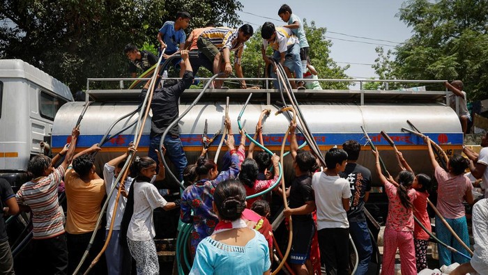 Warga India Berebut Air Bersih di Tengah Cuaca Panas Ekstrem Residents fill their containers with drinking water from a municipal tanker on a hot summer day in New Delhi, India, May 21, 2024. REUTERS/Adnan Abidi