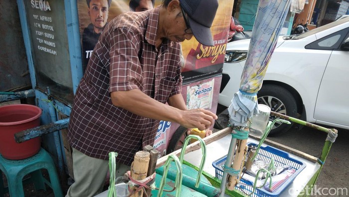 Tabroni di depan gerobak es serut miliknya.