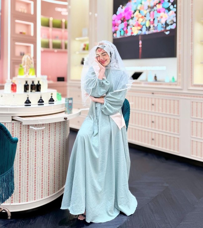 Melody Prima tampil anggun mengenakan gamis polos berpalet telur asin dan kerudung motif dalam tone putih. Ia mengenakan veil sebagai penanda bridal shower yang dibuat teman-temannya. Foto: Instagram @melodyprima