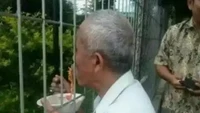 Terhalang pagar tak membuat pelanggan mie ayam ini gentar. Ia rela makan melalui sela-sela pagarnya agar tetap menyantap semangkuk mie ayam yang lezat. Foto: 1cak.com