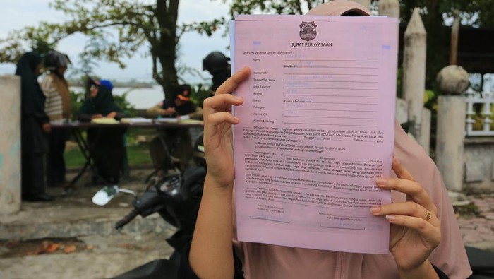 Warga yang terjaring dalam razia busana muslim memperlihatkan surat pernyataan di Desa Suak Indrapuri, Johan Pahlawan, Aceh Barat, Aceh, Jumat (24/5/2024). Razia penegakan peraturan daerah (qanun) nomor 11 tahun 2022 tentang Syariat Islam dengan melibatkan Satpol PP dan aparat TNI/Polri tersebut berhasil menjaring 76 pelanggar yang memakai yang tidak sesuai syariat. ANTARA FOTO/Syifa Yulinnas/YU