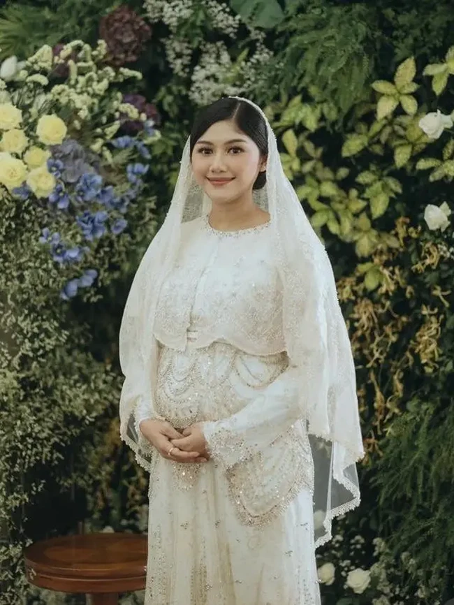 Erina Gudono dan Kaesang Pangarep pertama kali mengumumkan kehamilannya saat keduanya tengah umroh di tanah suci. Kini sudah semakin besar, menantu Jokowi itu juga terlihat sudah menggelar acara tasyakuran kehamilan anak pertamanya di Istana Bogor, Jawa Barat. Di acara tasyakuran tersebut Erina tampil cantik mengenakan dress putih. Foto: Instagram