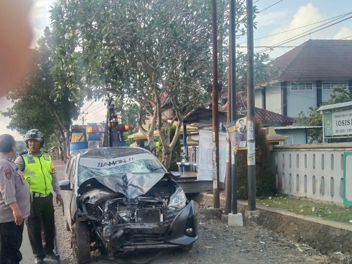 Petugas kepolisian mengevakuasi mobil yang terlibat kecelakaan dengan sepeda motor di jalan raya Sumpiuh-Kemranjen, Kabupaten Banyumas, Minggu (26/5/2023).